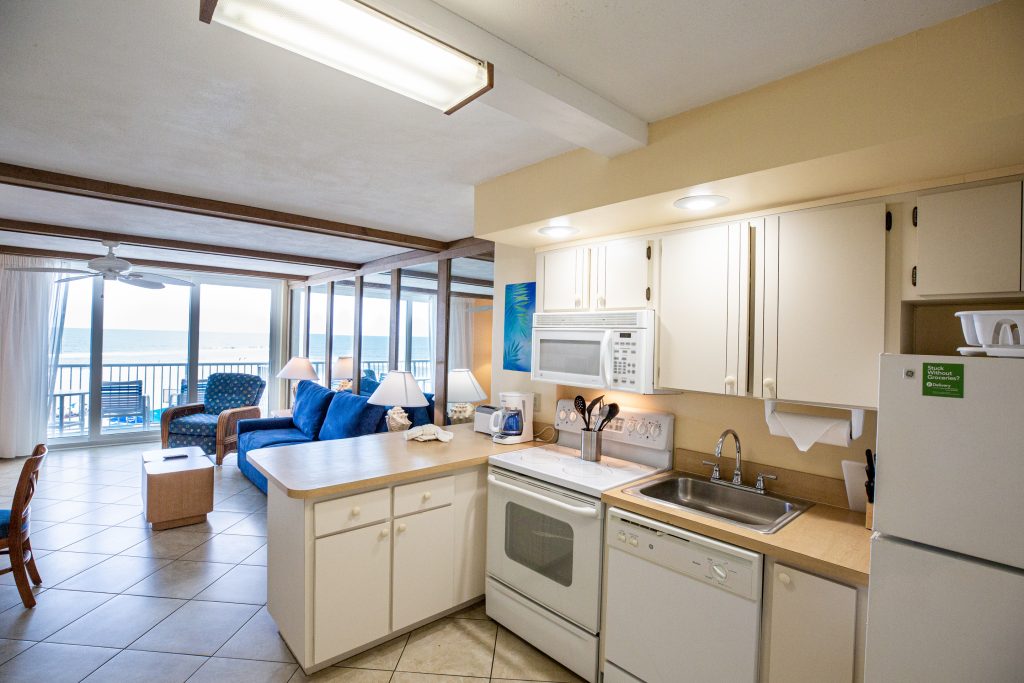 A wide view of a kitchen and living area with a balcony overlooking the ocean.