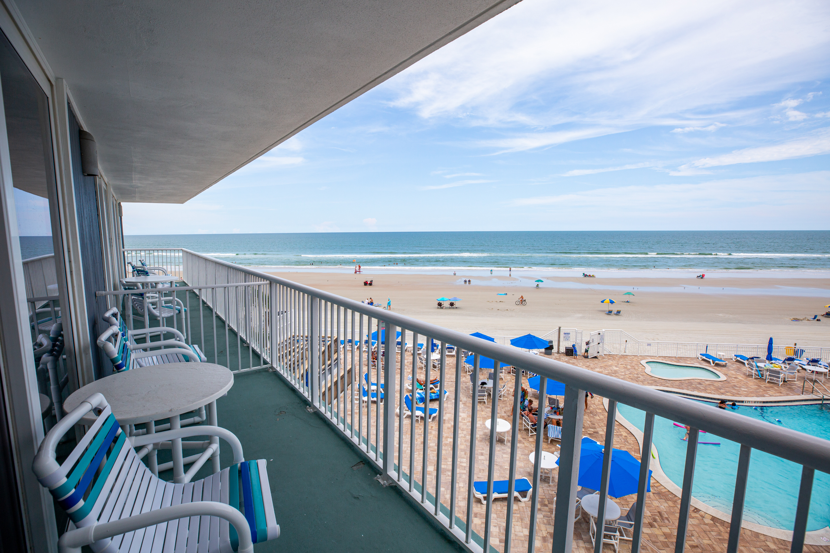 A balcony with a view of the beach and pool area.